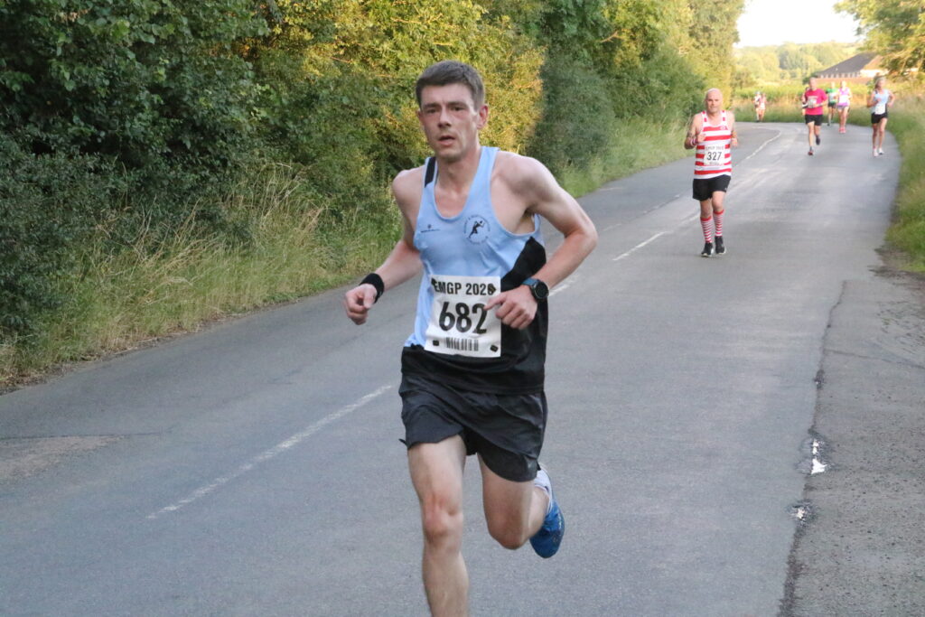 Main runner in the foreground, with other runners in the background during a race