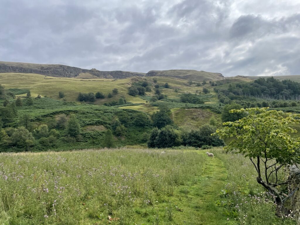 View of rolling hills, with Alport Castles high on the hill in the background